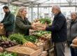 Menschen reichen sich in einer genossenschaftlichen Markthalle frisches Gemüse weiter